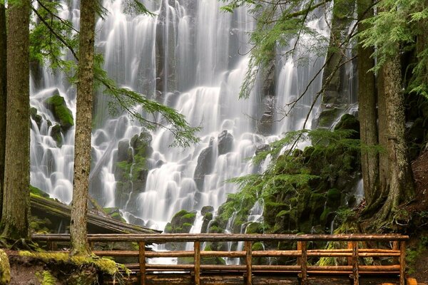 Holzbalkenbrücke vor dem Hintergrund eines Wasserfalls