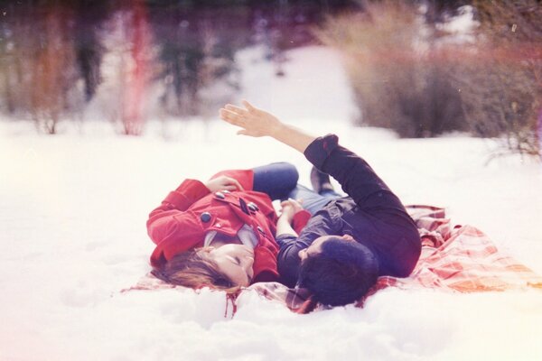 Fille avec un mec couché sur la neige