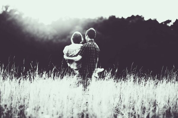 A girl in the arms of a man with her back in nature