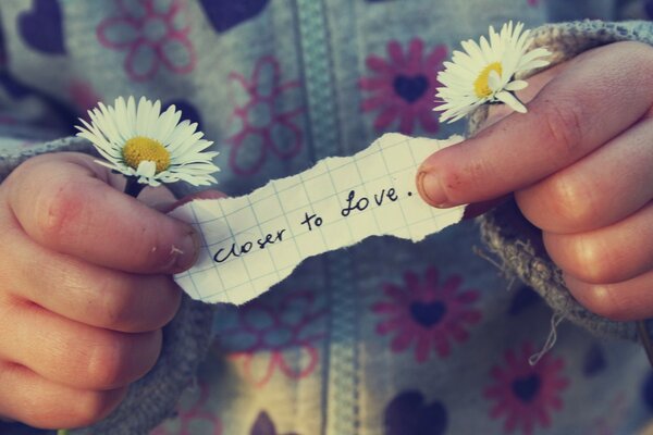 A child holds a note and daisies