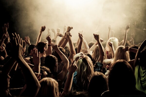 A crowd of people at a concert with their hands up