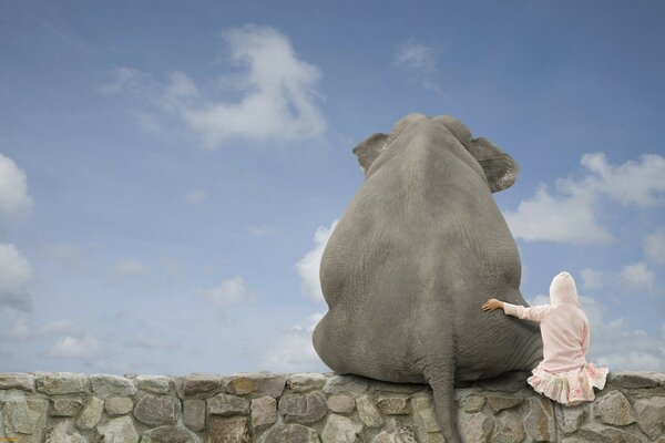 A girl in an embrace with an elephant against the sky