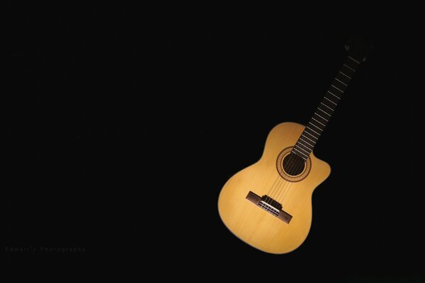 Musical guitar made of wood on a black background