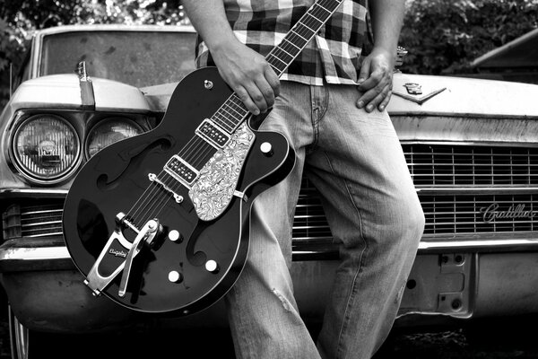 Un homme avec une guitare près d une voiture