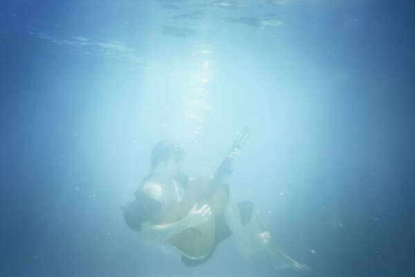 Immagine di un musicista con una chitarra sott acqua