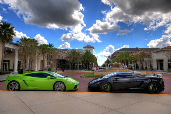 A light green and a black car are facing each other under a cloudy sky