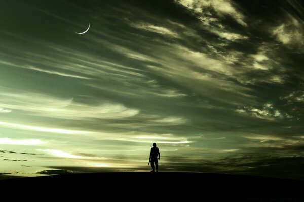 Photo of a traveler on foot against the background of a restless sky