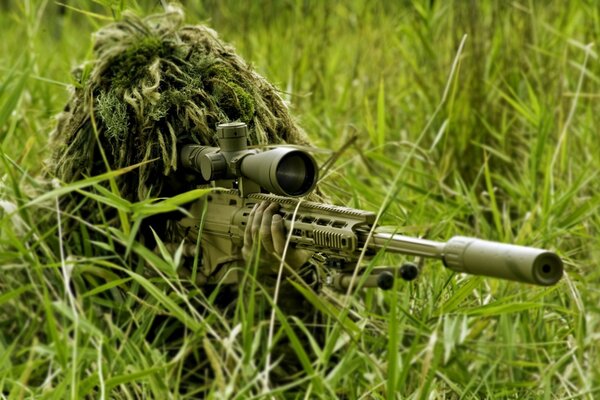 Ein Scharfschütze mit einem Gewehr im Gras zielt darauf ab