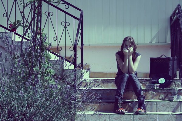 The girl is sitting on the stairs with a suitcase