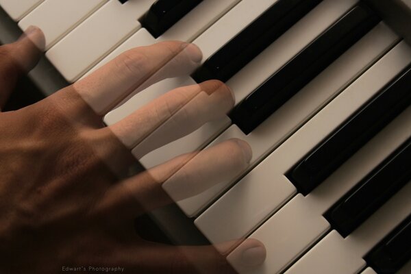 A hand playing on black and white piano keys