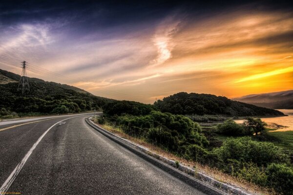 In lontananza autostrada al tramonto tra la vegetazione verde