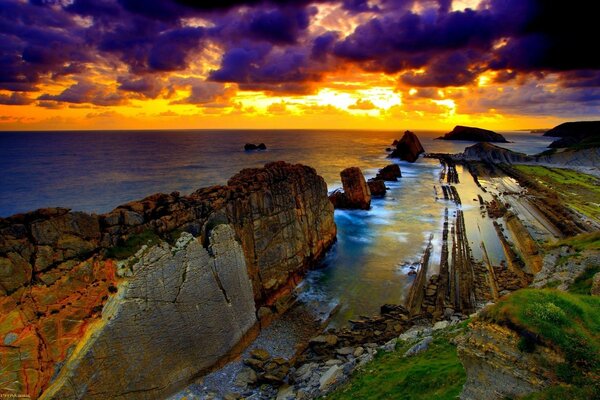 As cores marcantes da paisagem com rochas e mar ao pôr do sol