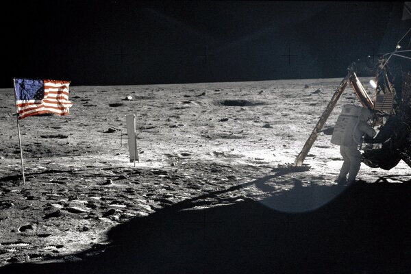 An astronaut on the surface of the moon with a US flag