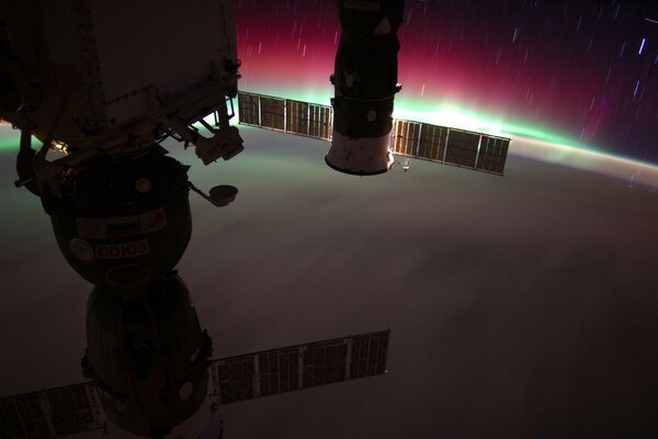 Photo of a spacecraft from space against the background of the Northern lights