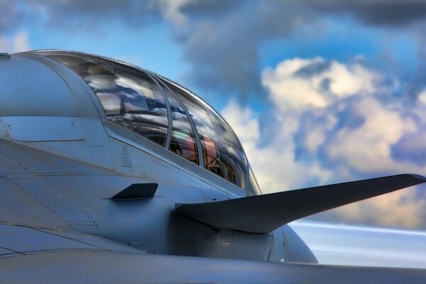 The fuselage of a military fighter against the background of clouds