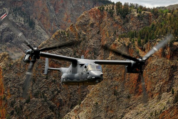 The helicopter flies between rocks with trees