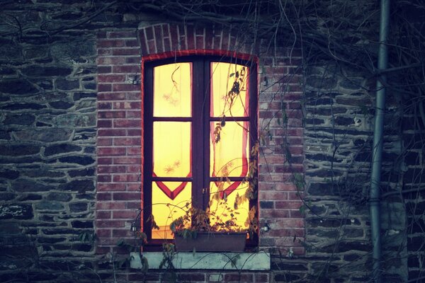 Ein leuchtendes Fenster hinter den Vorhängen in einem alten Haus