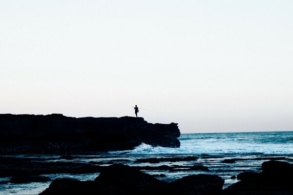 A man with a fishing rod on the seashore