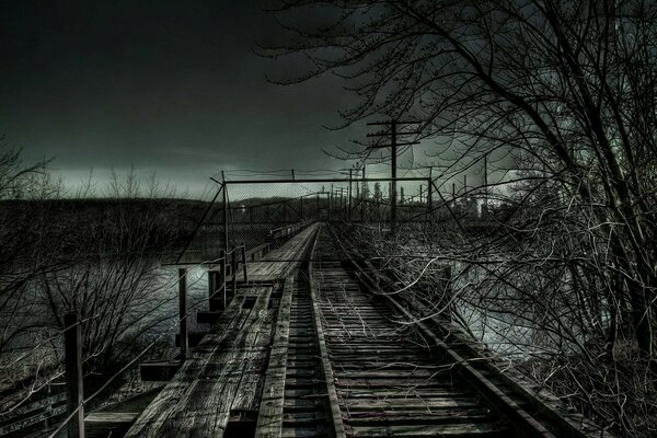 Paisaje de un ferrocarril con un puente de madera en el crepúsculo