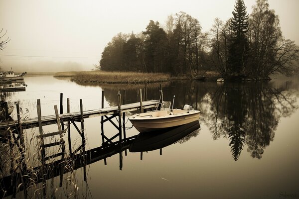 A picture with a boat and a lake with a forest reflection