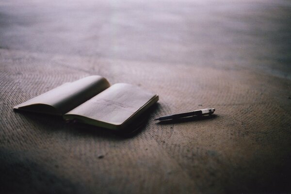 Ordinateur portable et livre avec stylo sur la plage