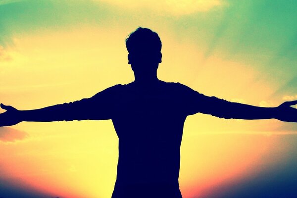 Black male silhouette against the sky with sunset illumination