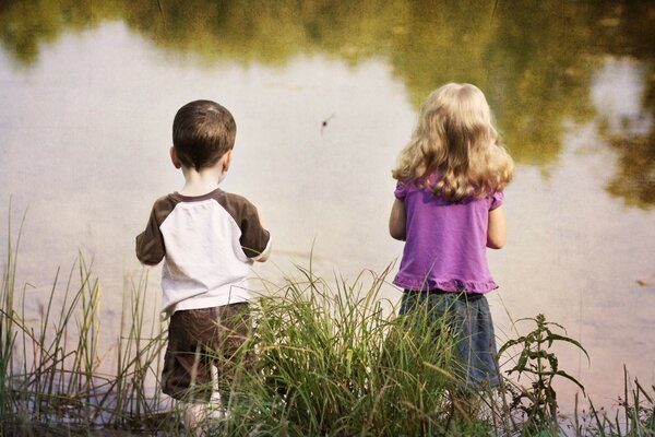 I bambini stanno sulla riva dello stagno