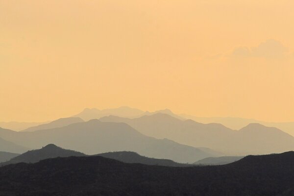 Photo of mountains in the fog on the background of sunset