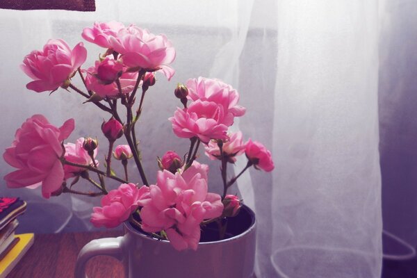 Foto minimalista de flores Rosadas en una taza sobre el fondo de las cortinas