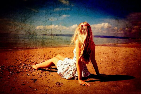 A girl in a dress lies on the shore to the water