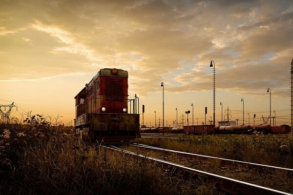 Demiryolu treni demiryolu yolunda koşar, üstündeki gökyüzü sessizce parlar, gün batımının yankısı rüzgarda yüzer