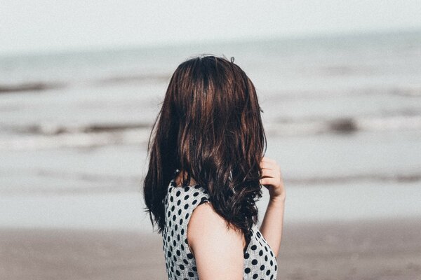 Chica de pelo oscuro en la orilla del mar