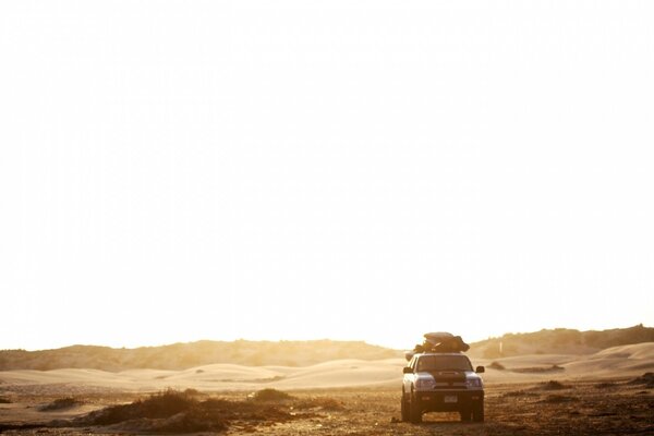 A lone SUV is driving through the desert