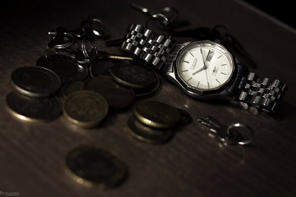 Clock on the table with coins and keychain