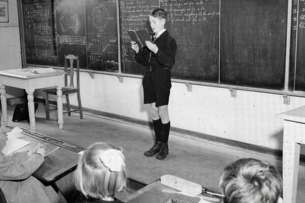 A student reads an old photo in front of the class