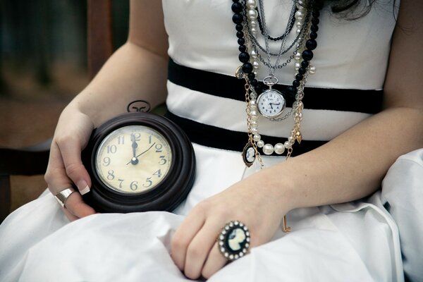 Mujer adulta en vestido blanco con reloj en su regazo