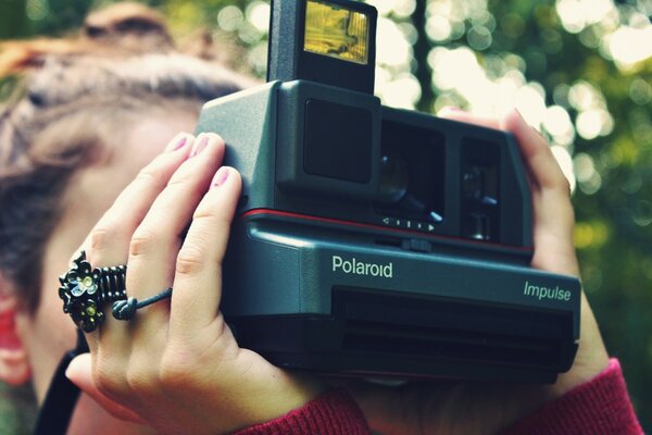 A girl takes pictures on a polaroid in the forest