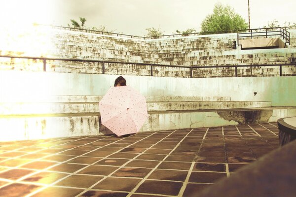 A girl hid behind an umbrella in an abandoned stadium