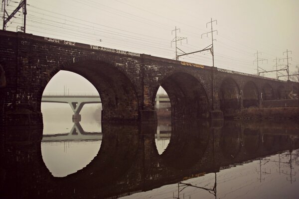 Puente de piedra sobre el agua con reflexión