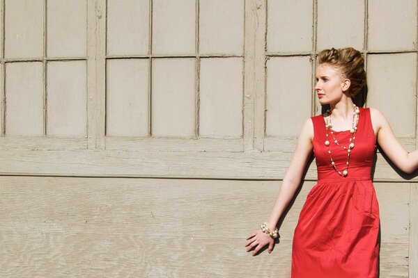 Chica con vestido rojo contra la pared