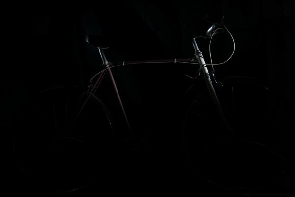 A small beam of light illuminates a small part of the bike in the dark