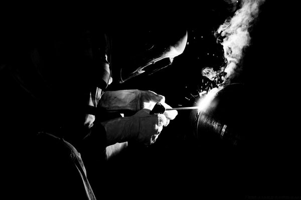 Welder cooks metal on a dark background