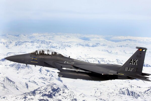 Black fighter jet over snow-covered mountains