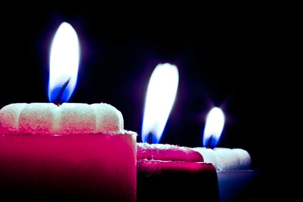 The flame of multicolored candles on a dark background