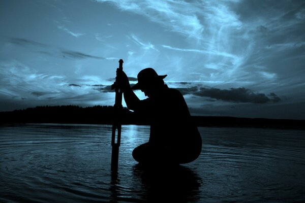 Silhouette of a man in a hat against the background of water and sky