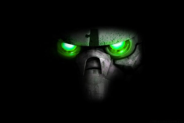 On a black background, a mask with green burning eyes