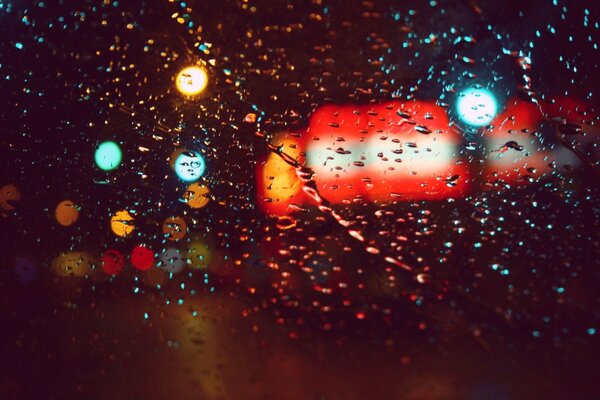 Gotas de lluvia en el cristal a la luz de las linternas