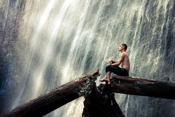 Hombre en un árbol en el fondo de una cascada