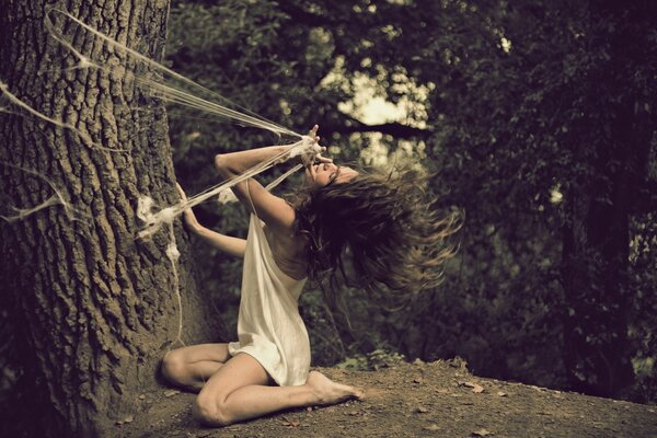 Creative image of a girl, a spider web and a tree