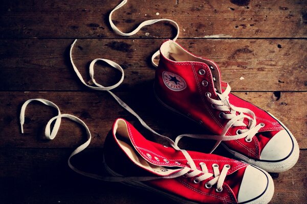 Sneakers rosse su fondo in legno e iscrizione con lacci 365